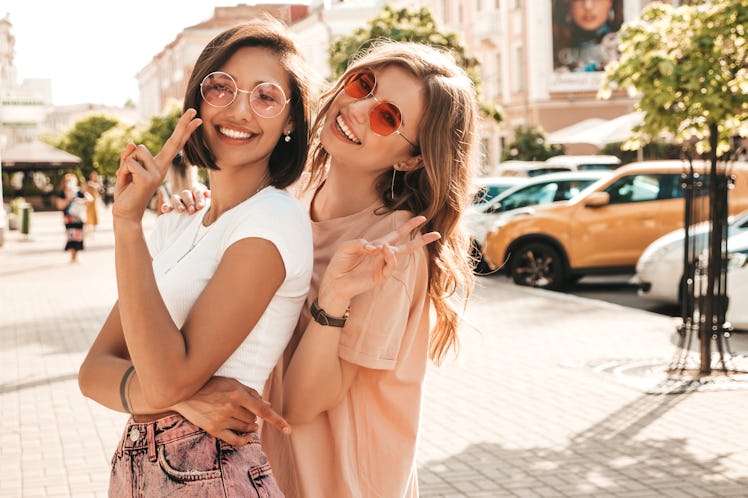 Two young beautiful smiling hipster girls in trendy summer clothes.Sexy carefree women posing on the...