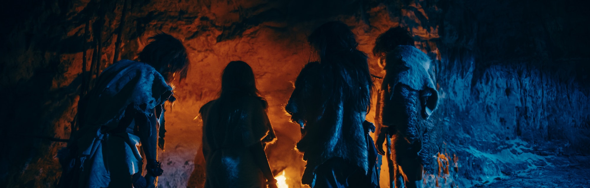 Tribe of Prehistoric Hunter-Gatherers Wearing Animal Skins Live in a Cave at Night. Neanderthal or H...