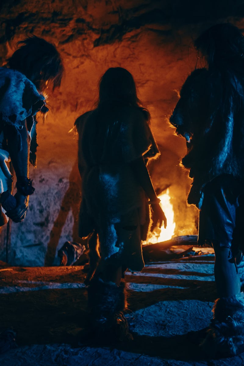 Tribe of Prehistoric Hunter-Gatherers Wearing Animal Skins Live in a Cave at Night. Neanderthal or H...