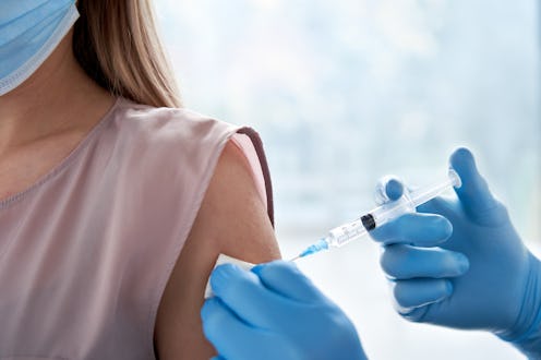 Male doctor holding syringe making covid 19 vaccination injection dose in shoulder of female patient...