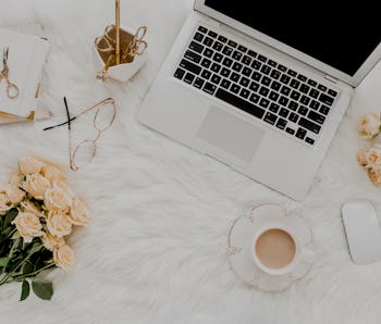 Female workspace with laptop, roses flowers bouquet, golden accessories, notebook, glasses. Flat lay...