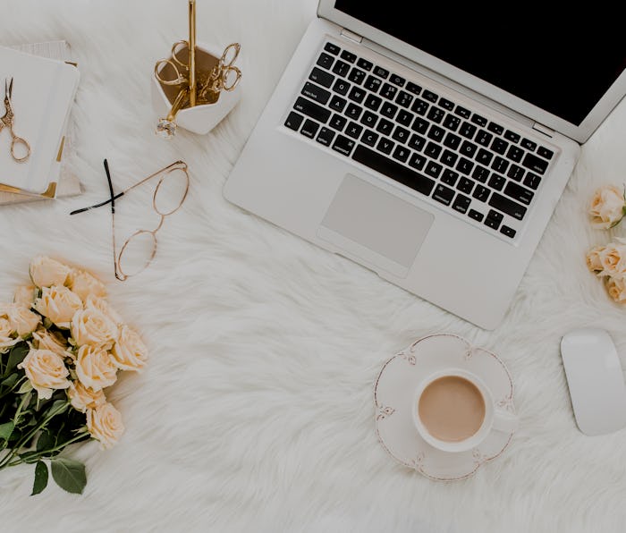 Female workspace with laptop, roses flowers bouquet, golden accessories, notebook, glasses. Flat lay...