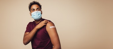 Man wearing face mask showing his vaccinated arm. Man in protective face mask received a corona vacc...