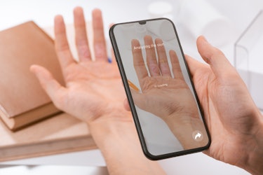 Man using a phone app to recognize a disease on inner side of his fingers. AI algorithm identifies s...