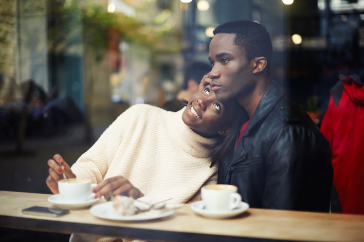 Portrait of young couple in love having coffee in a cafe and smiling.