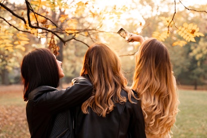 ladies , with beautiful hair styles, taking picture of them in park in fall season the week of Novem...