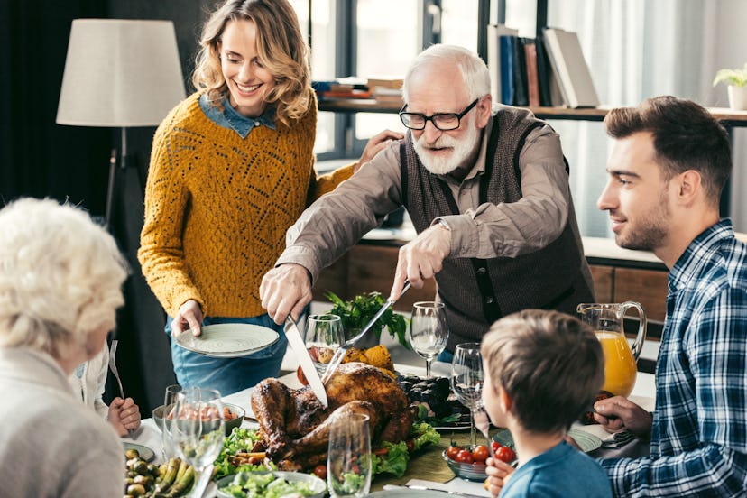 grandfather cutting turkey for family on thanksgiving dinner