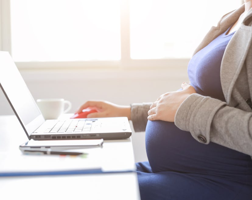 anonymous pregnant woman working on laptop computer