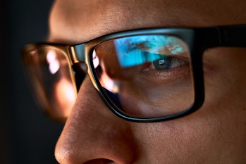 Close up view of focused businessman wears computer glasses for reducing eye strain blurred vision l...