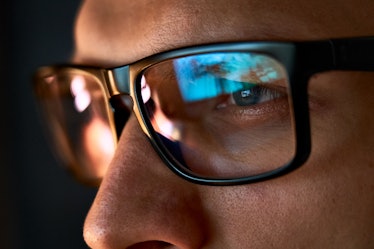Close up view of focused businessman wears computer glasses for reducing eye strain blurred vision l...