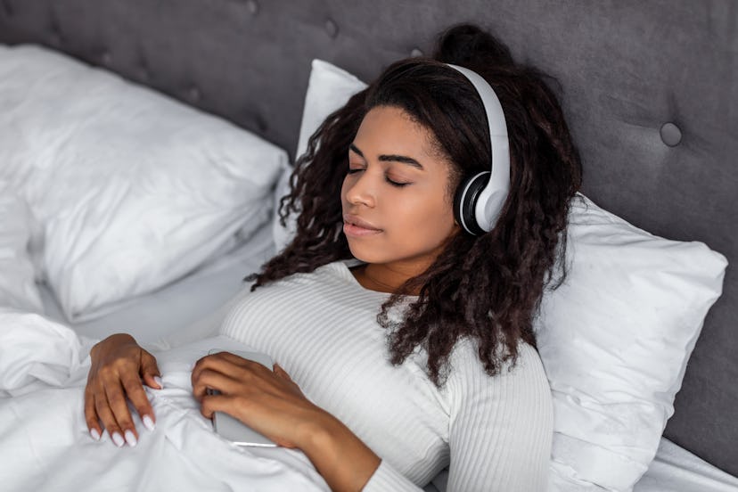woman in bed wearing headphones