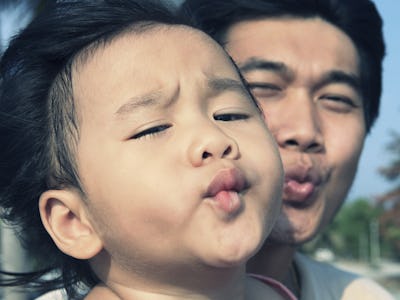 baby kid and father funny kissing mouth take a photo on location