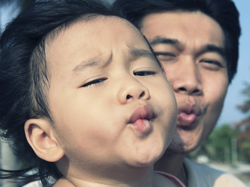 baby kid and father funny kissing mouth take a photo on location