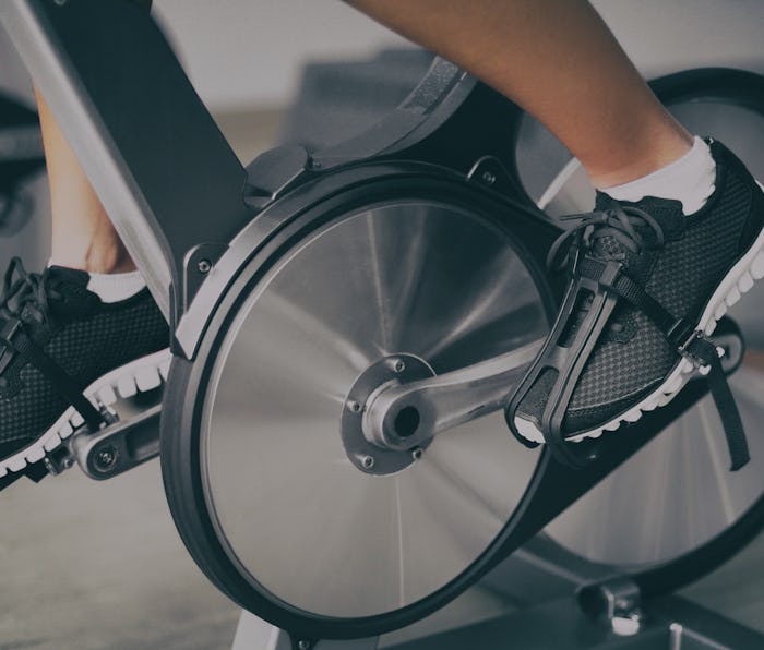 Fitness machine at home woman biking on indoor cycling stationary bike exercise indoors for cardio w...