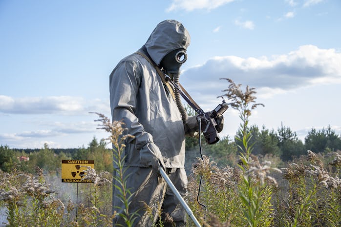 A military man dressed as chemical troops is examining the radioactive territory; a radio station si...