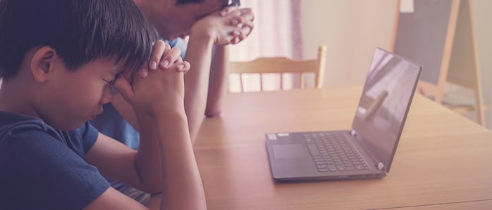 Preteen boy praying with father parent with laptop, family and kids worship online together at home,...
