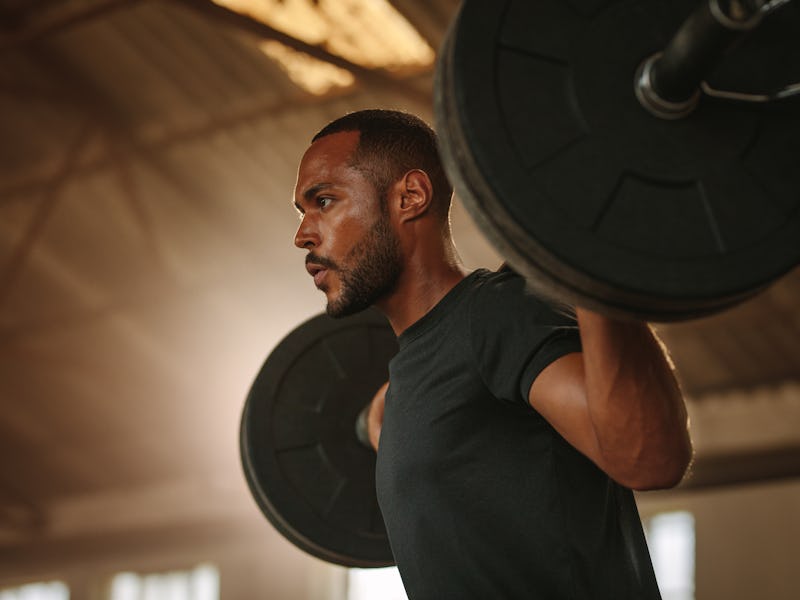 Man exercising with barbell. Male bodybuilder doing weight lifting workout at gym.