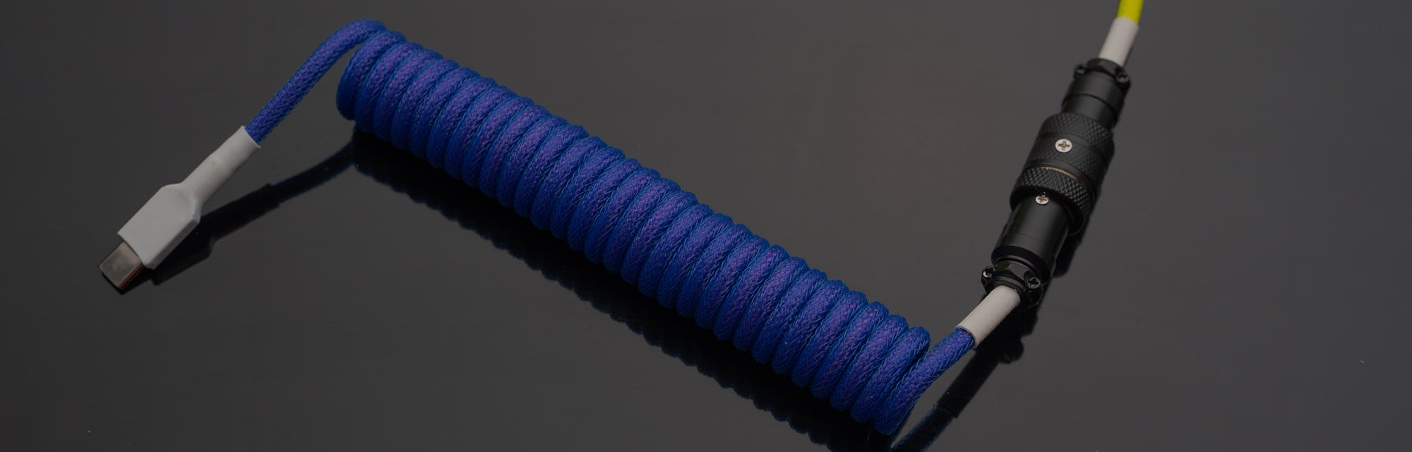 A close up image of a stylish coiled USB cable with aviator connector for keyboarr enthusiast 