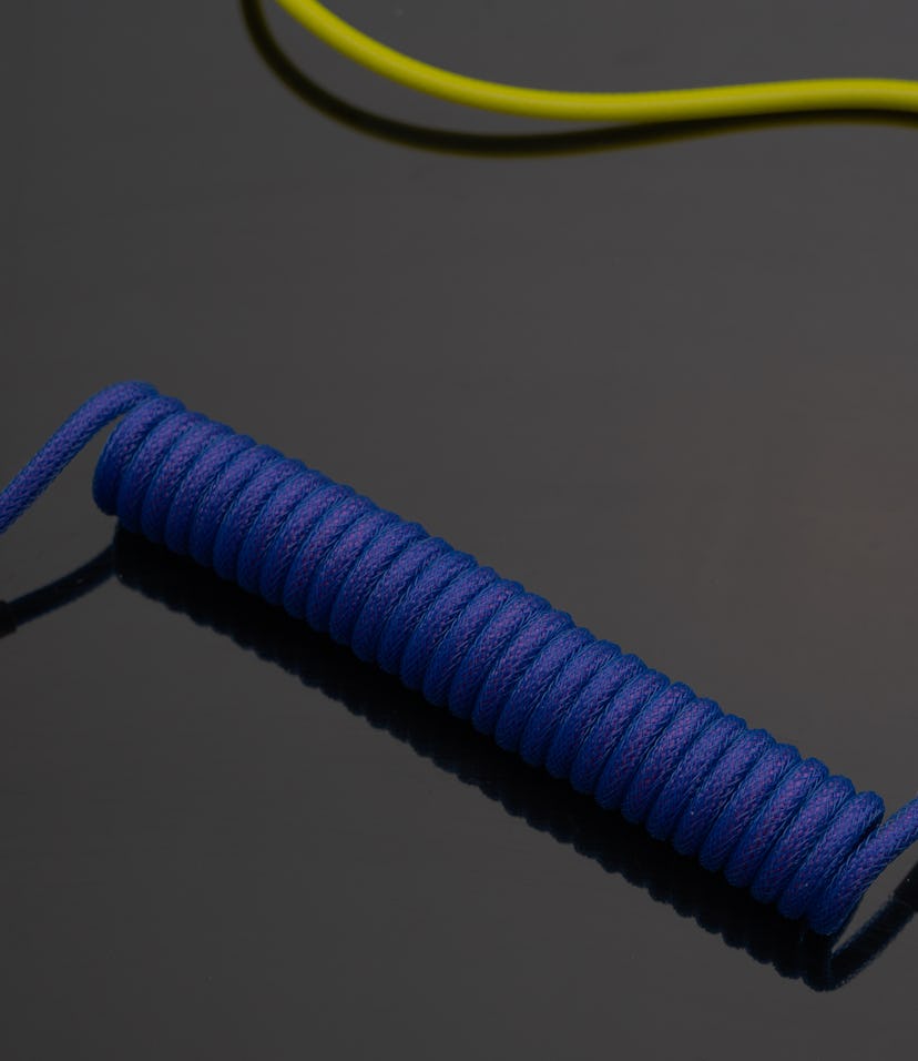 A close up image of a stylish coiled USB cable with aviator connector for keyboarr enthusiast