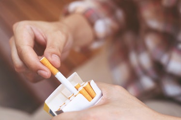 close up man hand holding peel it off cigarette pack prepare smoking a cigarette. Packing line up. p...