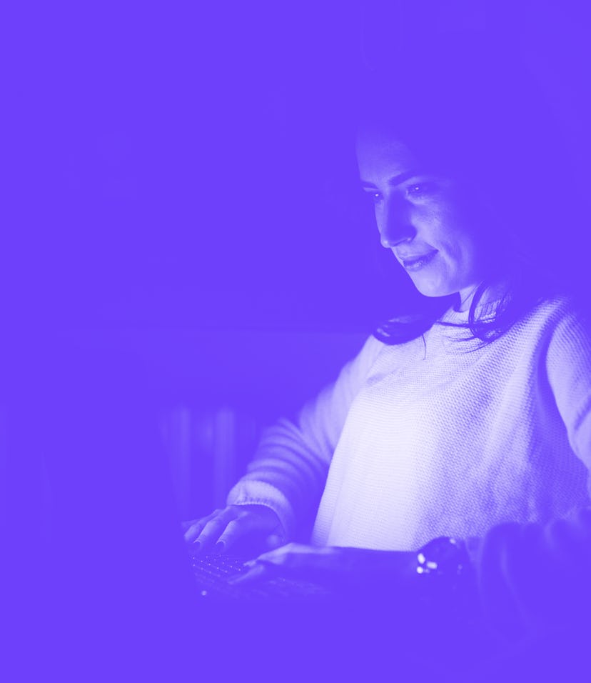 Young woman indoors at home using computer late at night finishing deadline project doing business o...