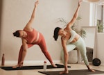 Two female friends trying some yoga poses for 2.