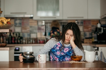 Tired mother, trying to pour coffee in the morning. Woman lying on kitchen table after sleepless nig...