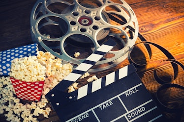 Cinema concept of vintage film reels, clapperboard and other tools on old wooden background.