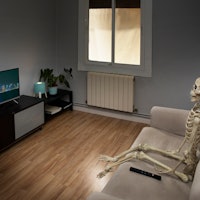 Lonely skeletón watching TV on a couch