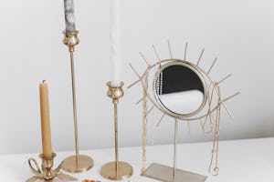 Modern golden boho mirror with pearl necklaces on it, which is part of a pearlcore aesthetic.