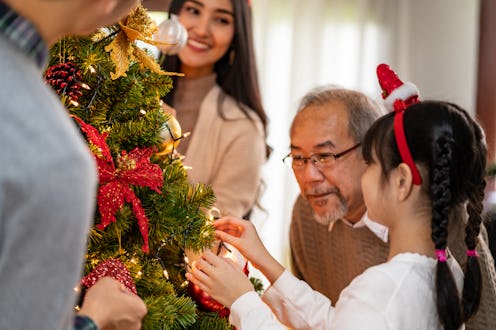 Multigenerational asian Family decorating a Christmas tree. Mom Dad daughter girl and grandfather de...