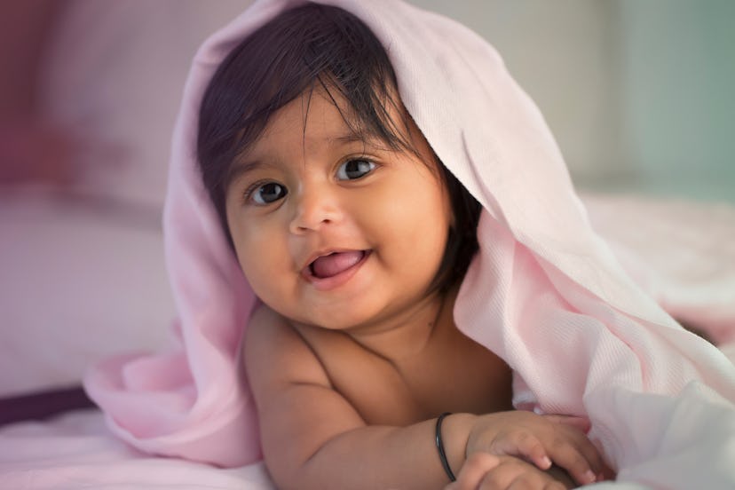 A baby girl under a pink blanket in a list of girl names that start with L