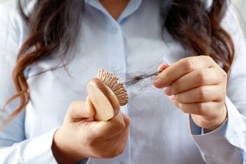 A woman removing the lost hair from a brush