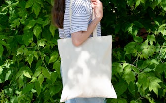 Empty reusable canvas tote bag mockup. Natural canvas eco-friendly shopper bag on girl's shoulder. M...