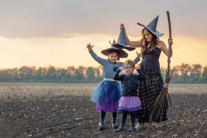 Happy Halloween. cheerful family of witches flies on a broomstick. Mother and children in costumes a...