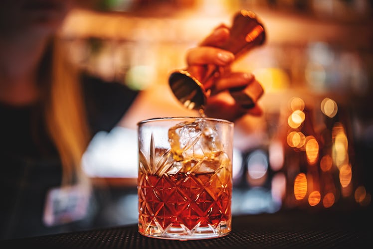woman bartender hand making negroni cocktail. Negroni classic cocktail and gin short drink with swee...