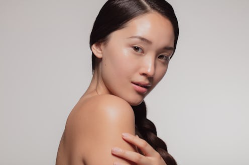 Attractive young asian woman with glowing skin. Korean female with beautiful skin looking at camera ...