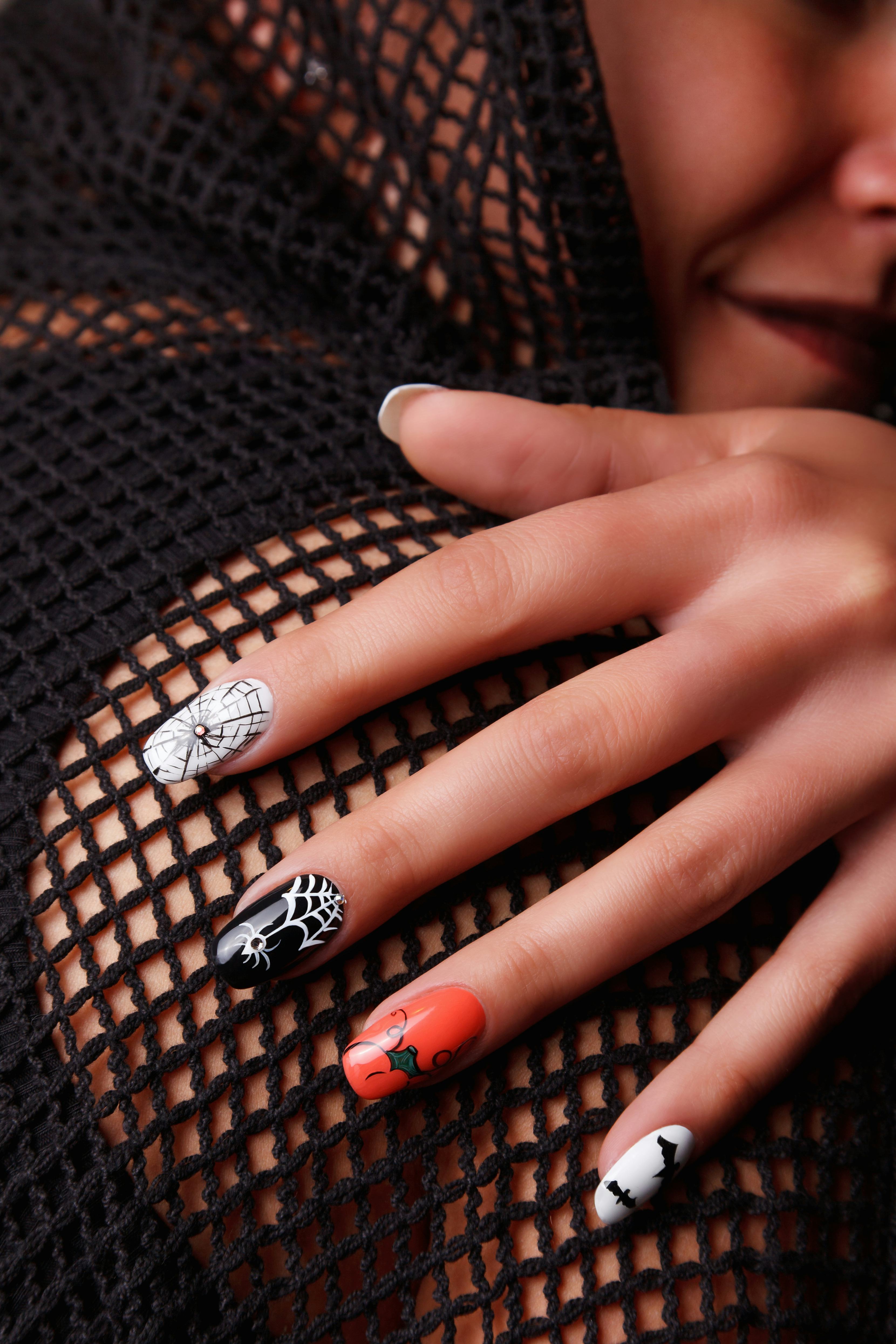These Halloween nails feature orange, black, and white designs with spiderwebs, bats, and swirls.
