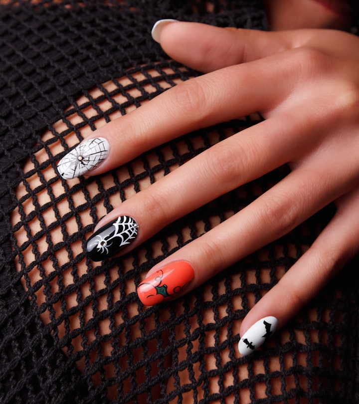 These Halloween nails feature orange, black, and white designs with spiderwebs, bats, and swirls.