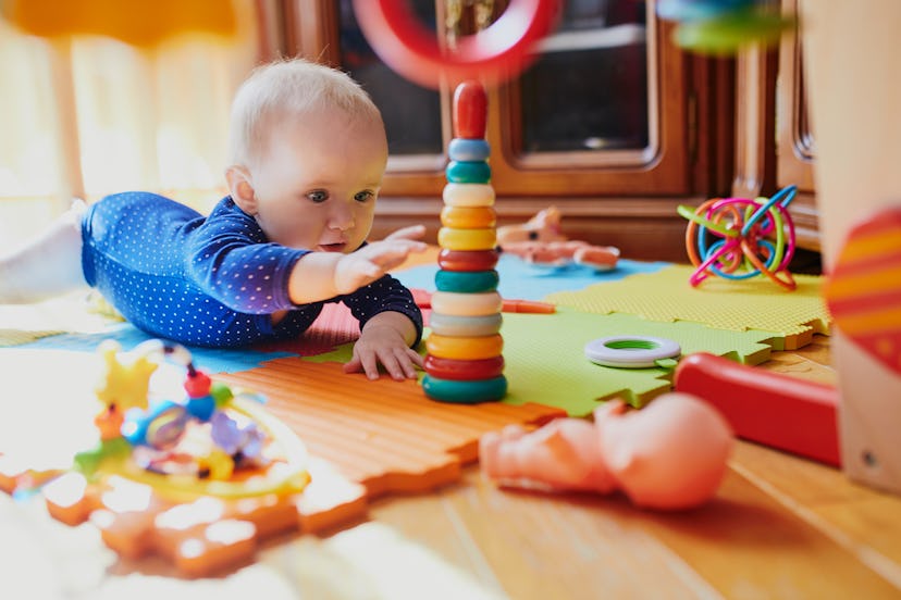 Baby girl playing with toys on the floor. Happy healthy little child at home