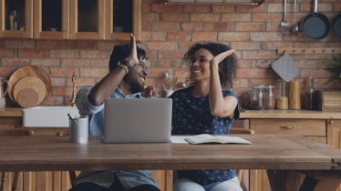 Happy successful Afro American couple celebrating financial achieve at laptop, giving high five. Mar...