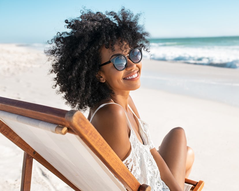 smiling woman on the beach thinking about her cancer horoscope 2023
