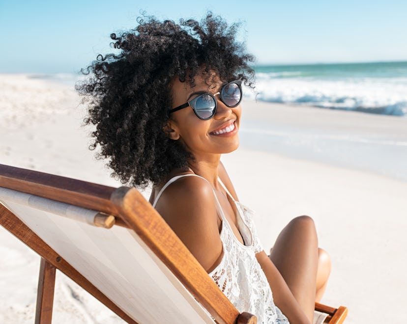 smiling woman on the beach thinking about her cancer horoscope 2023 