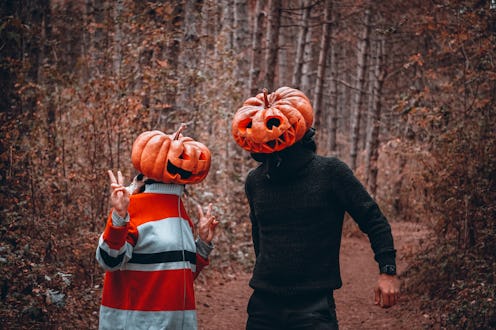 Two people with carved out pumpkins on their heads as their Halloween costumes