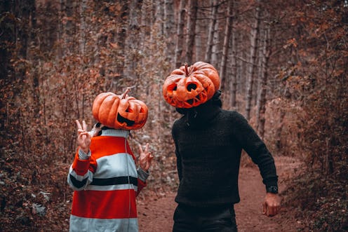 Two people with carved out pumpkins on their heads as their Halloween costumes 