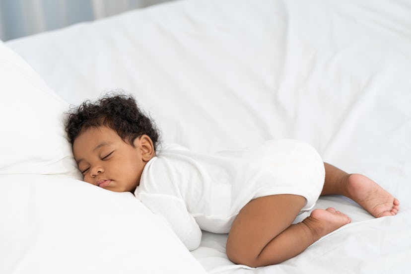 Black baby named Beau, meaning love, asleep on a white mattress