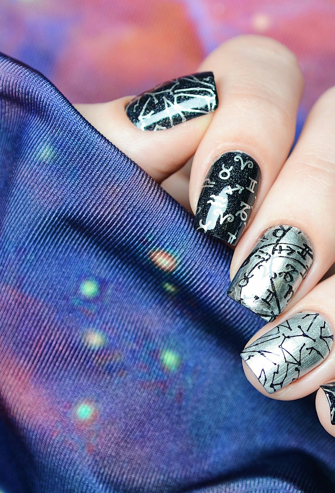 Black and silver manicure with a constellation map pattern on a cosmic background, representative of...