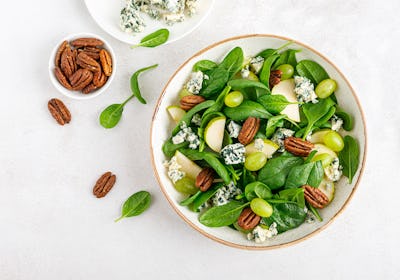 Salad of spinach, pear, grape, pecan and gorgonzola cheese with lemon dressing. Healthy food, diet. ...