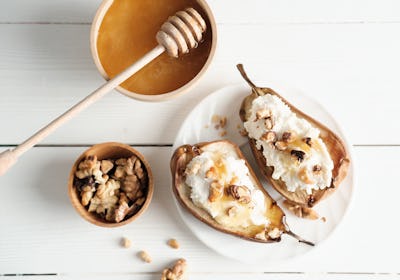autumn menu dessert, baked pears with cream cheese and honey topping with nuts. fall season comforti...