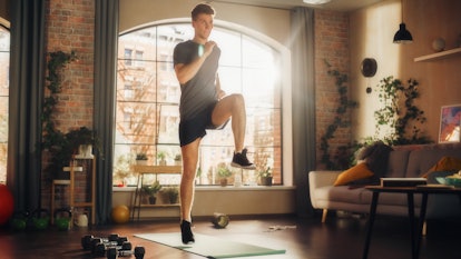 一名男子在家里的瑜伽垫上做高膝运动。